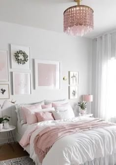 a white bedroom with pink accents and pictures on the wall above the bed, along with a chandelier