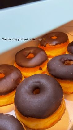 there are many donuts in the box on the table and one has chocolate frosting