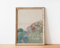 a painting is hanging on the wall next to a wooden shelf with an empty frame