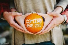 two people holding a pumpkin with the words coming june written on it