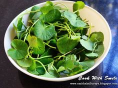 a white bowl filled with green leaves on top of a table