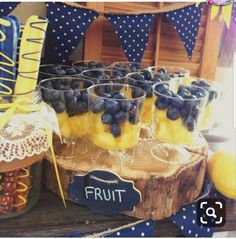 blueberries and lemons are arranged in glasses on a table with other fruit items