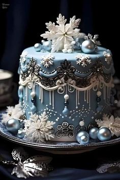 a blue and white cake with snowflakes on it's sides sitting on a plate