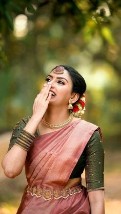 a woman in a sari is holding her hand to her face and looking up