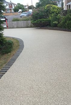 an empty parking lot in the middle of a residential area with trees and bushes on either side