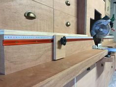 a table sawing on top of a piece of wood in a room with cabinets