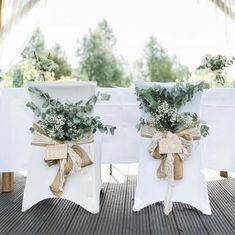 two white chairs with bows and flowers on them are sitting in front of each other