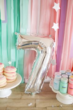 a number seven balloon sitting on top of a table next to cakes and cupcakes