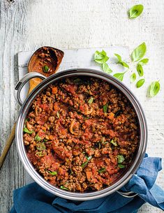 a large pot filled with meat and vegetables on top of a wooden cutting board next to bread