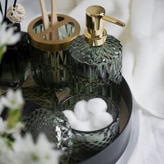 two soap dispensers sitting on top of a black tray next to white flowers