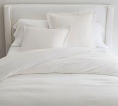 a bed with white sheets and pillows on it