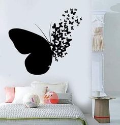 a black butterfly wall sticker on the side of a bed in a room with white walls