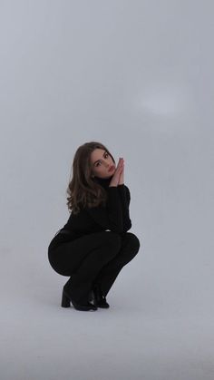 a woman kneeling down with her hand on her face and looking up at the sky