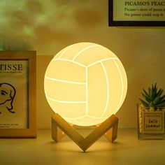 a lit up volleyball ball sitting on top of a table next to a potted plant