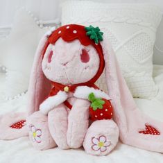 a pink stuffed animal sitting on top of a bed next to a white pillow and blanket