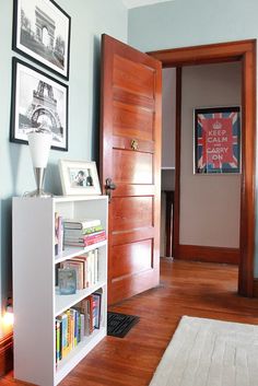 a living room with a book shelf and pictures on the wall next to an open door