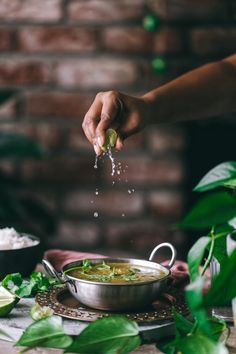 a person sprinkling salt onto a bowl of soup