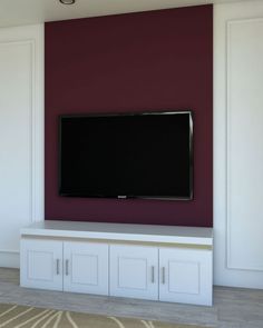 a flat screen tv mounted to the side of a wall in a room with white cabinets