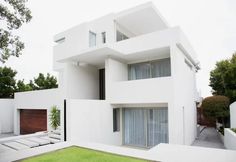 a white modern house with grass in front