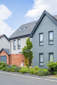 a row of houses next to each other on a street with trees and bushes in front of them