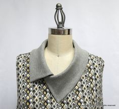 a mannequin wearing a gray and yellow sweater with geometric designs on the collar