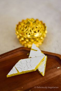 two pieces of cake sitting on top of a wooden tray next to a golden object