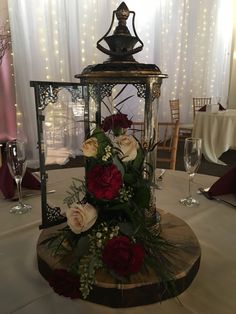 a centerpiece with flowers and greenery on a table