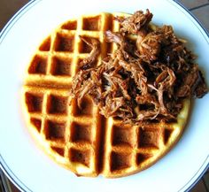 a white plate topped with waffles covered in meat