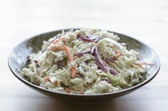 a bowl filled with coleslaw on top of a wooden table