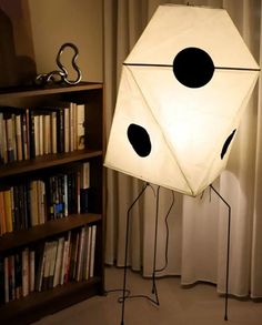 a lamp that is sitting on a stand in front of a book shelf with books