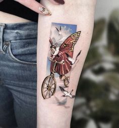 a woman with a tattoo on her arm is riding a bike and birds are flying around