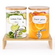 two glass jars filled with fruit juice on a wooden stand next to each other,