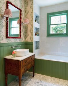 a bathroom with green and white wallpaper has a sink, mirror and tub in it