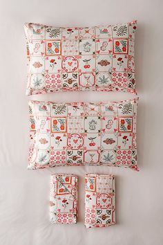 three pillows and one pillow case on a white surface