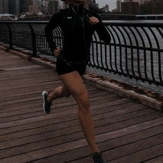 a woman running across a bridge in the rain