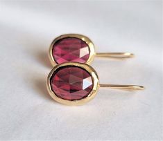 "These red, oval solid gold Garnet earrings were made in a classic and chic design to create your go-to earrings for days and nights. These gold red gemstone earrings were 100% handmade and are a perfect gift for those celebrating their birthdays in January. Garnet is the official January birthstone and shines beautifully in the gold setting in a deep wine-red color. It brings abundance, prosperity, and success. It builds self-confidence, inspiration, and creativity, and increases commitment, ho Oval Birthstone Earrings For Formal Occasions, Yellow Gold Oval Earrings With Birthstone, Oval Yellow Gold Earrings Gift, Oval Ruby Earrings Gift, Red Oval Birthstone Earrings, Gold Oval Birthstone Earrings, Oval Gold Birthstone Earrings, Drop Gold Earrings, Birthday Earrings