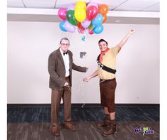 two men standing next to each other holding balloons