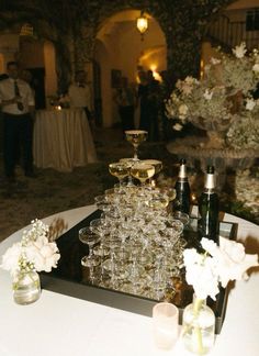 a table topped with lots of glasses filled with champagne next to vases and flowers