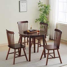 a dining room table with four chairs and a plant in the corner next to it