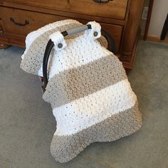 a crocheted blanket sitting on the floor next to a wooden dresser and chair