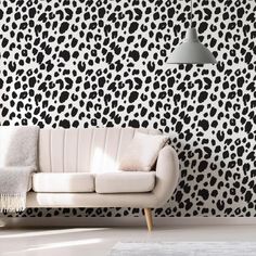 a white couch sitting in front of a wall with black and white animal print on it