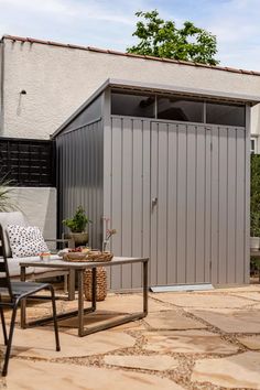 an outdoor patio with chairs, table and storage shed