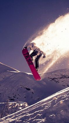 a man flying through the air while riding a snowboard on top of a snow covered slope