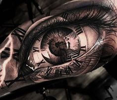 an eye tattoo on the arm with roman numerals and clock face in it