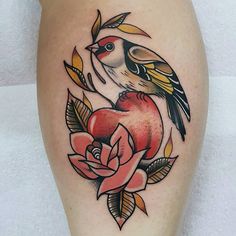 a bird sitting on top of a flower next to an apple with leaves around it