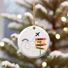 a christmas ornament hanging from a tree with lights in the background and an airplane painted on it