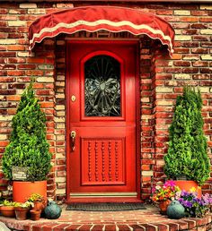 a red front door with potted plants and flowers