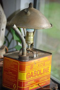 an old gas pump lamp sitting on top of a wooden table next to a window