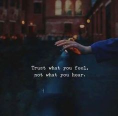 someone holding their hand out in front of a building with the words trust what you feel, not what you hear