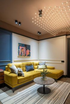 a living room with yellow couches and white rugs on the floor in front of a painting